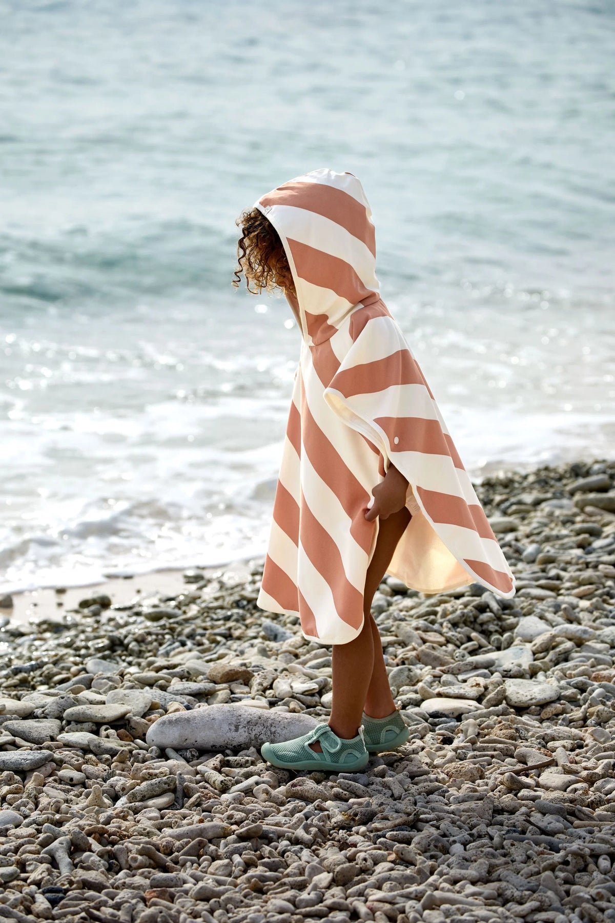 Kind trägt gestreiften Badeponcho am Strand von Lässig bei Bärechind Winterthur Zürich Schweiz