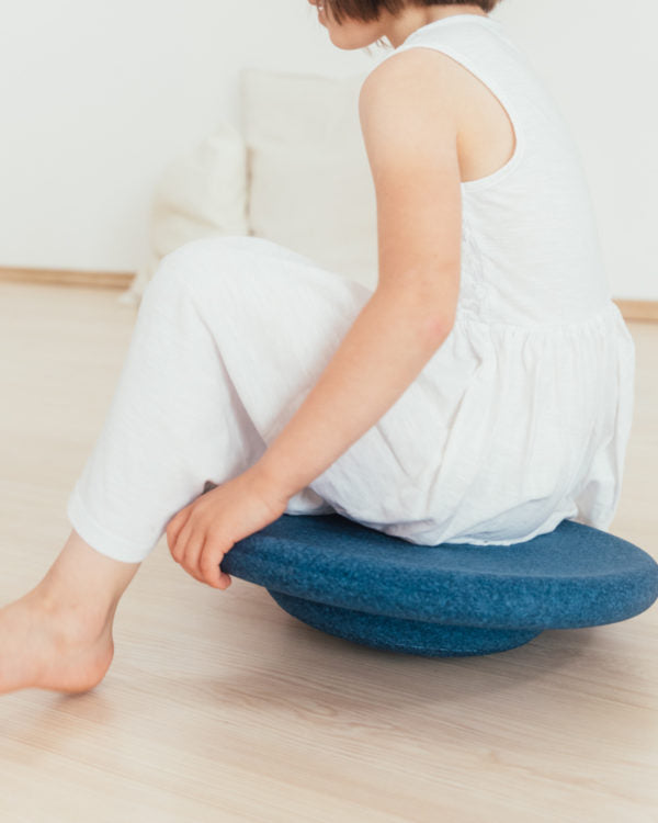 Kind sitzt entspannt auf dem Balance Board – kreative Sitzlösung mit Stapelstein bei Bärechind