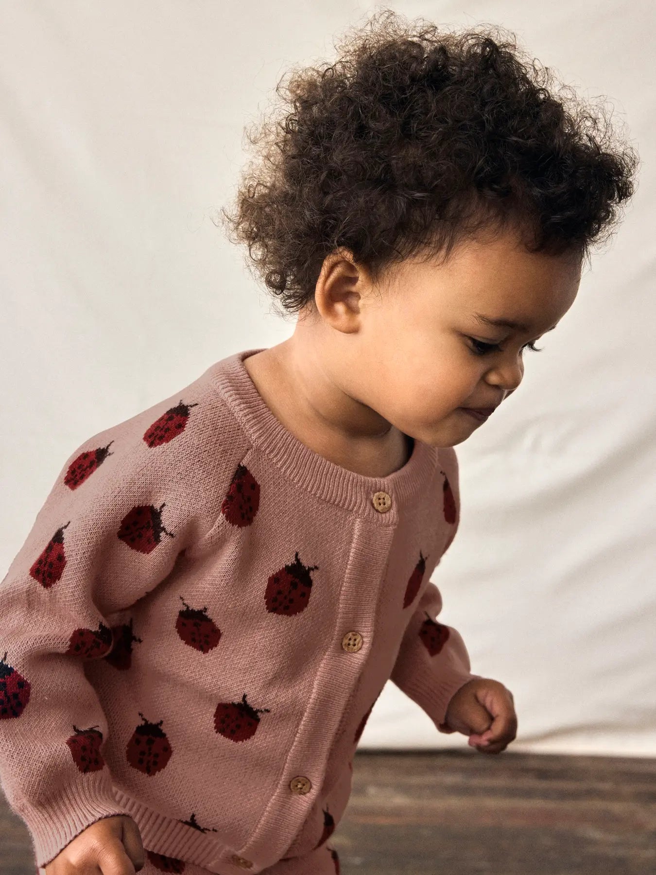 Kleinkind trägt Lil’Atelier Strickjacke mit Marienkäfer-Muster, erhältlich bei Bärechind in Winterthur, Zürich Schweiz.