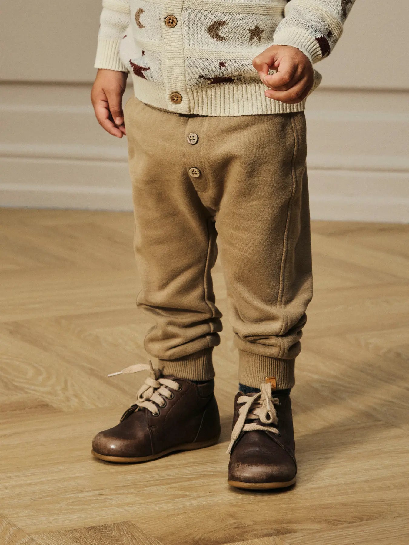 Kleinkind trägt beige Sweatpants von Lil'Atelier mit Knöpfen – erhältlich bei Bärechind in Winterthur, Zürich, Schweiz.