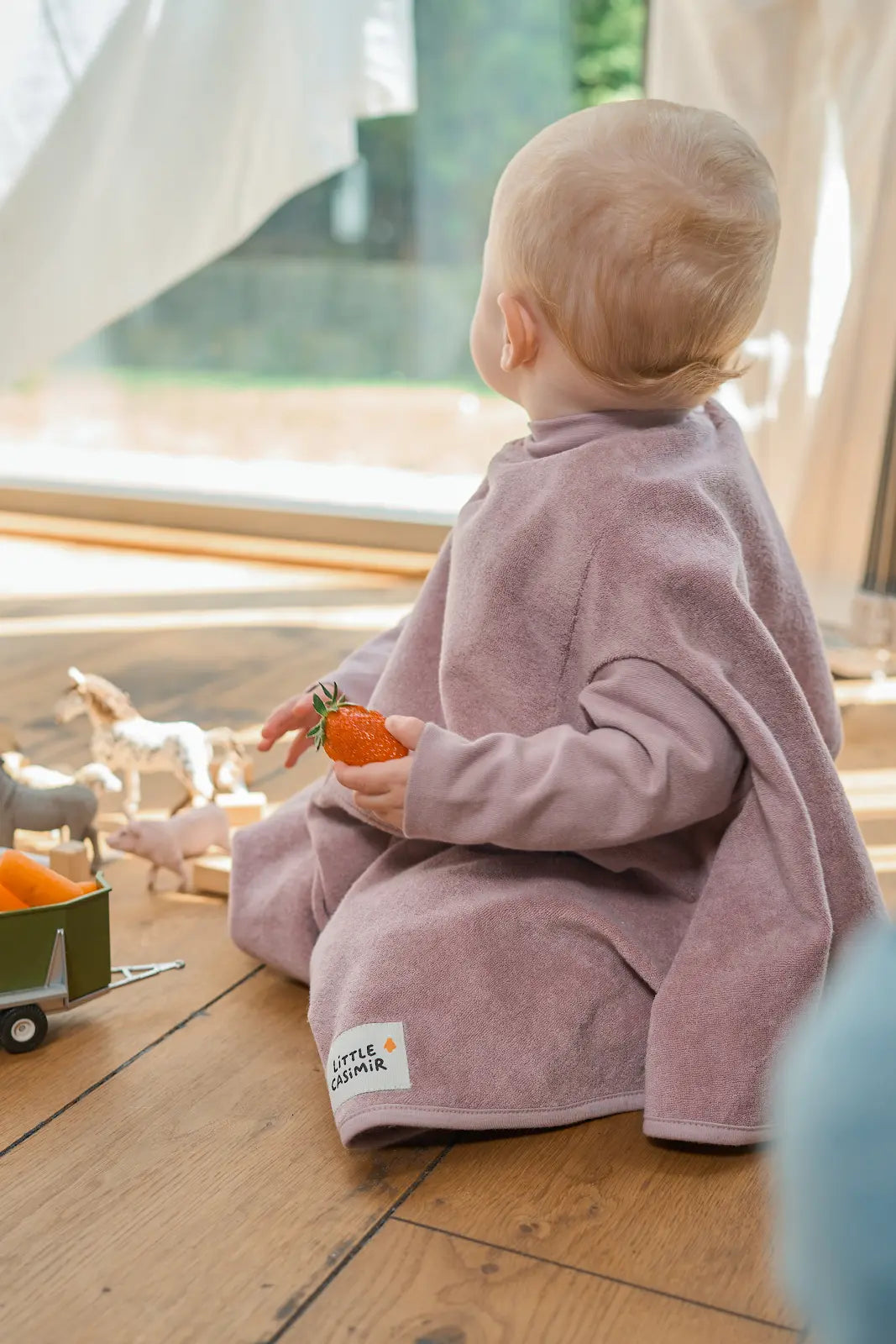 Kind trägt das wasserdichte Little Casimir Lätzchen Boo Lilac Love in Altrosa beim Essen und Spielen, erhältlich im Bärechind Winterthur