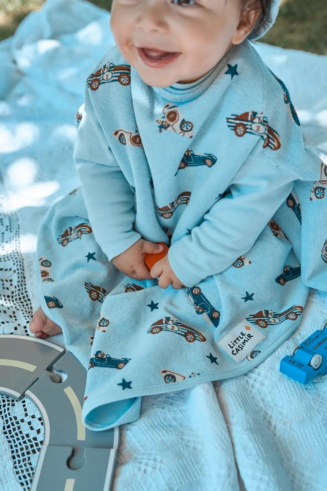 Kind trägt das wasserdichte Little Casimir Lätzchen Boo Sky Racers mit Ärmeln beim Spielen und Essen, erhältlich im Bärechind Winterthur