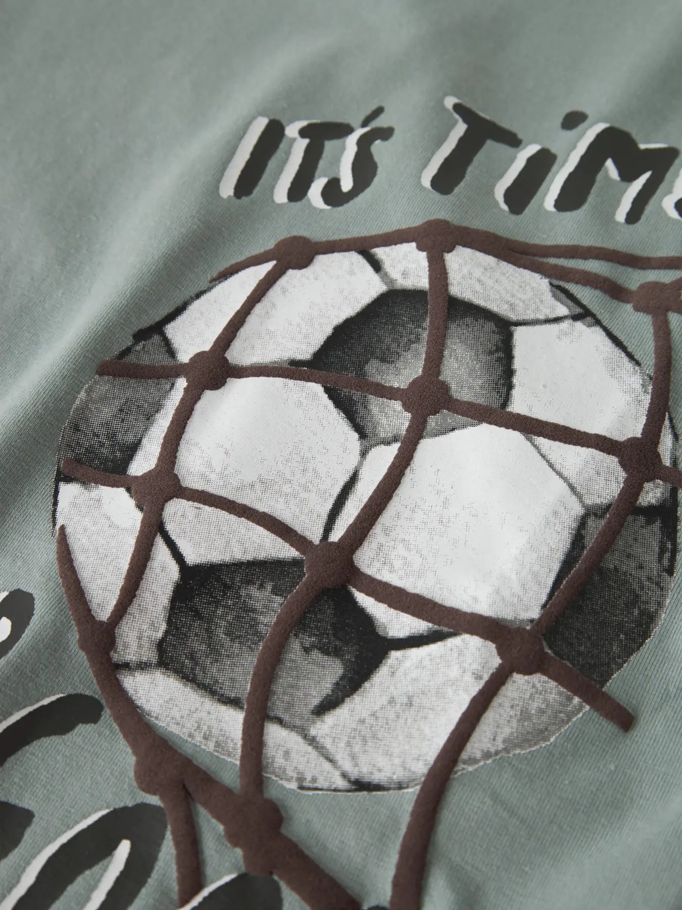 Detailaufnahme des Fussballmotivs und Schriftzugs auf dem NAME IT Langarmshirt, erhältlich im Bärechind.