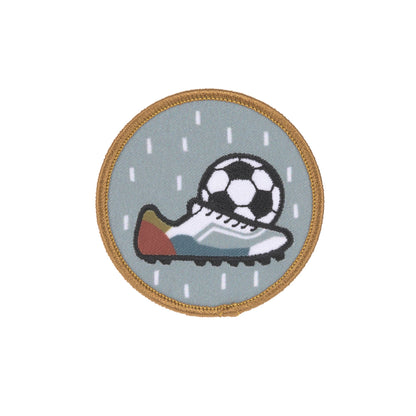 Runde Patch mit Fussball und Fussballschuh auf grauem Hintergrund aus dem Laessig Fussball Set.