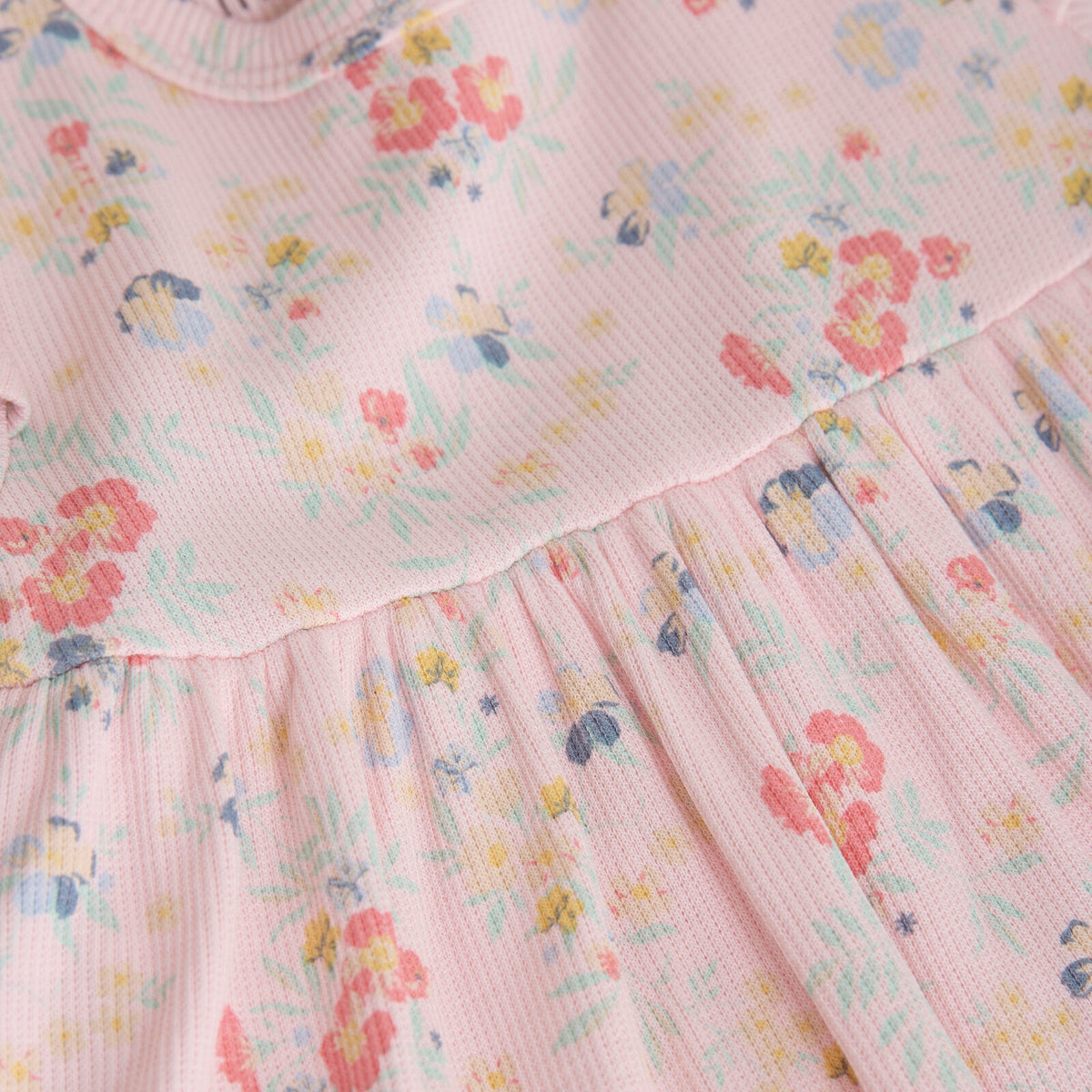 Nahaufnahme des weichen Rippstoffs mit Blumen-Allover-Print und verspielten Rüschenärmeln
