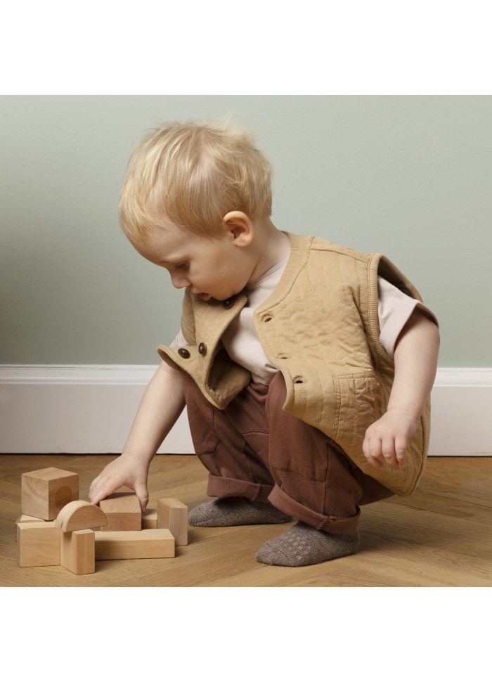 Baby trägt GoBabyGo Alpakawollsocken beim Spielen mit Holzspielzeug – rutschfest und wärmend