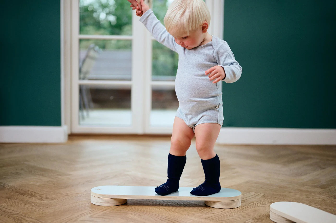 Baby mit navyefarbenen GoBabyGo Wollsocken auf Holzfussboden – sicherer Halt beim Laufenlernen