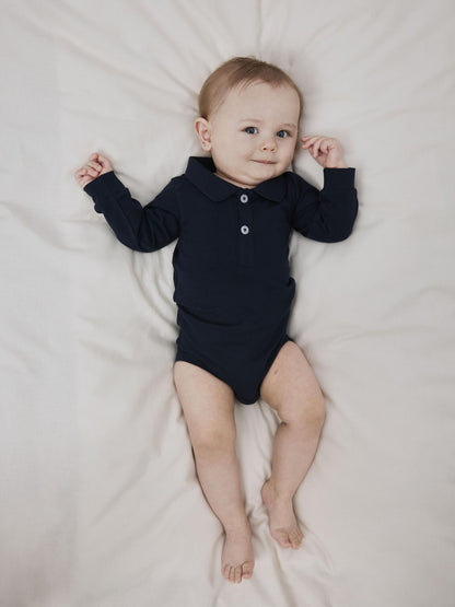 Baby trägt dunkelblauen Polo-Body von NAME IT, fotografiert im Bärechind in Winterthur, Zürich Schweiz.