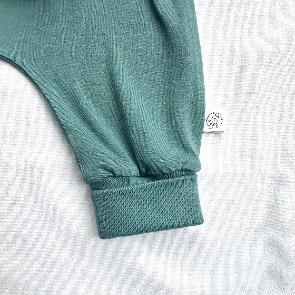 Detailaufnahme des Beinbündchens der salbeigrünen Babyhose mit bequemer Passform. Erhältlich im Bärechind Winterthur.