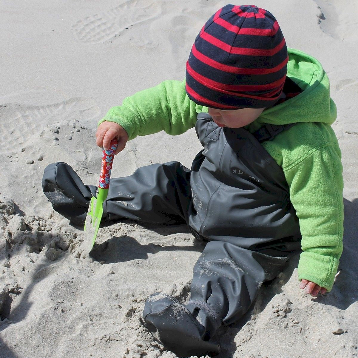 Kind mit BMS BabyBuddy Navy Regenhose beim Spielen im Sand