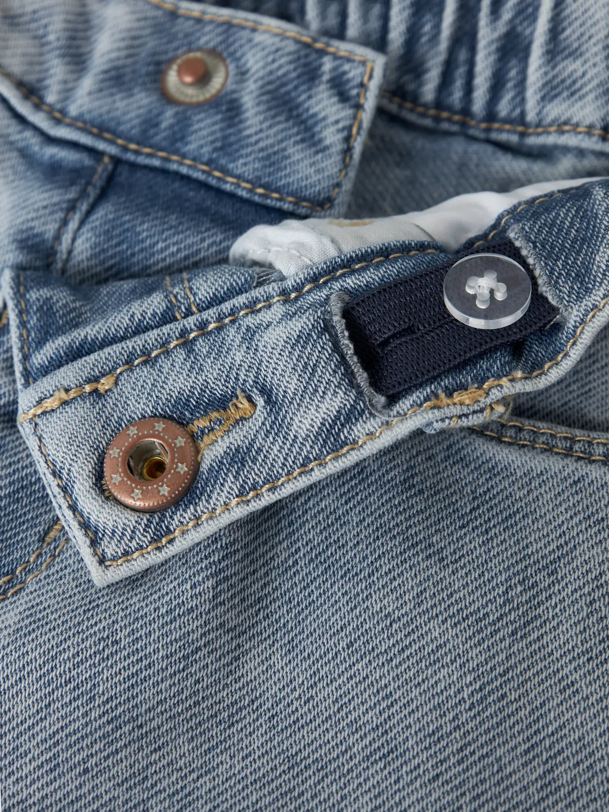Detailaufnahme von Knopf und Denimstoff der hellblauen Kinder Shorts von NAME IT, Bärechind Winterthur, Zürich, Schweiz.