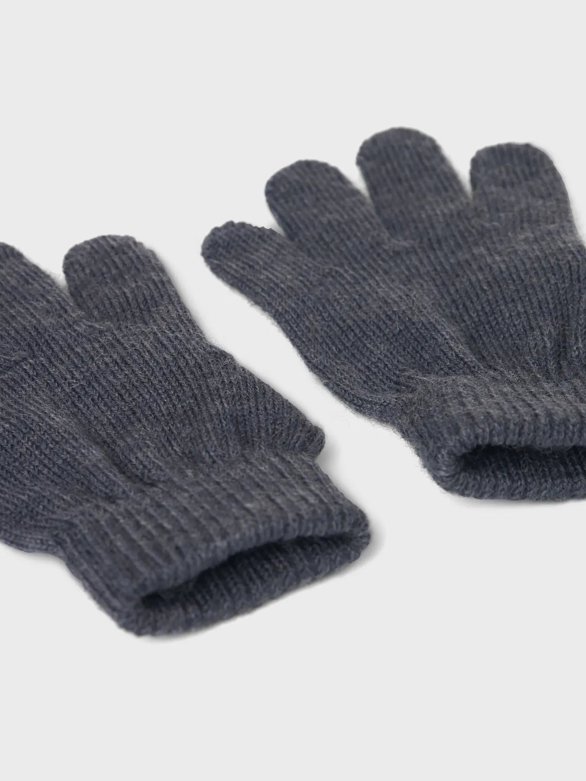 Nahaufnahme von Bündchen und Strickstruktur eines dunkelblauen Wollhandschuhe.


