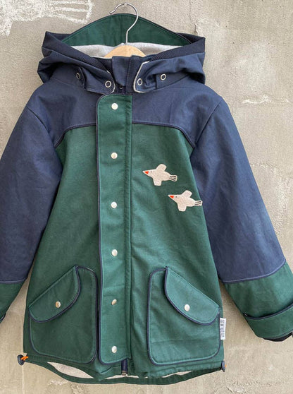 Das Bügelbild Vogel von Halfbird auf einer Kinder-Regenjacke als kreative Verzierung und Reparaturlösung. Erhältlich im Bärechind Winterthur.