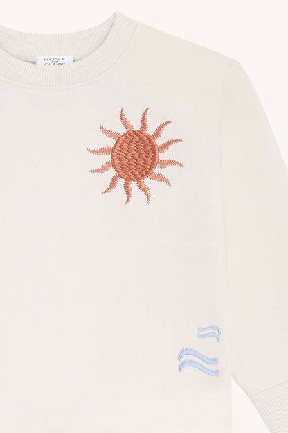 Detailansicht der Sonnenstickerei auf dem Hust&Claire Sejer Palms Sweatshirt, Bärechind Winterthur, Zürich, Schweiz.