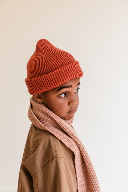 Kind trägt die beerenrote Merino Strickmütze mit Umschlag zu einem rosa Schal und beiger Jacke