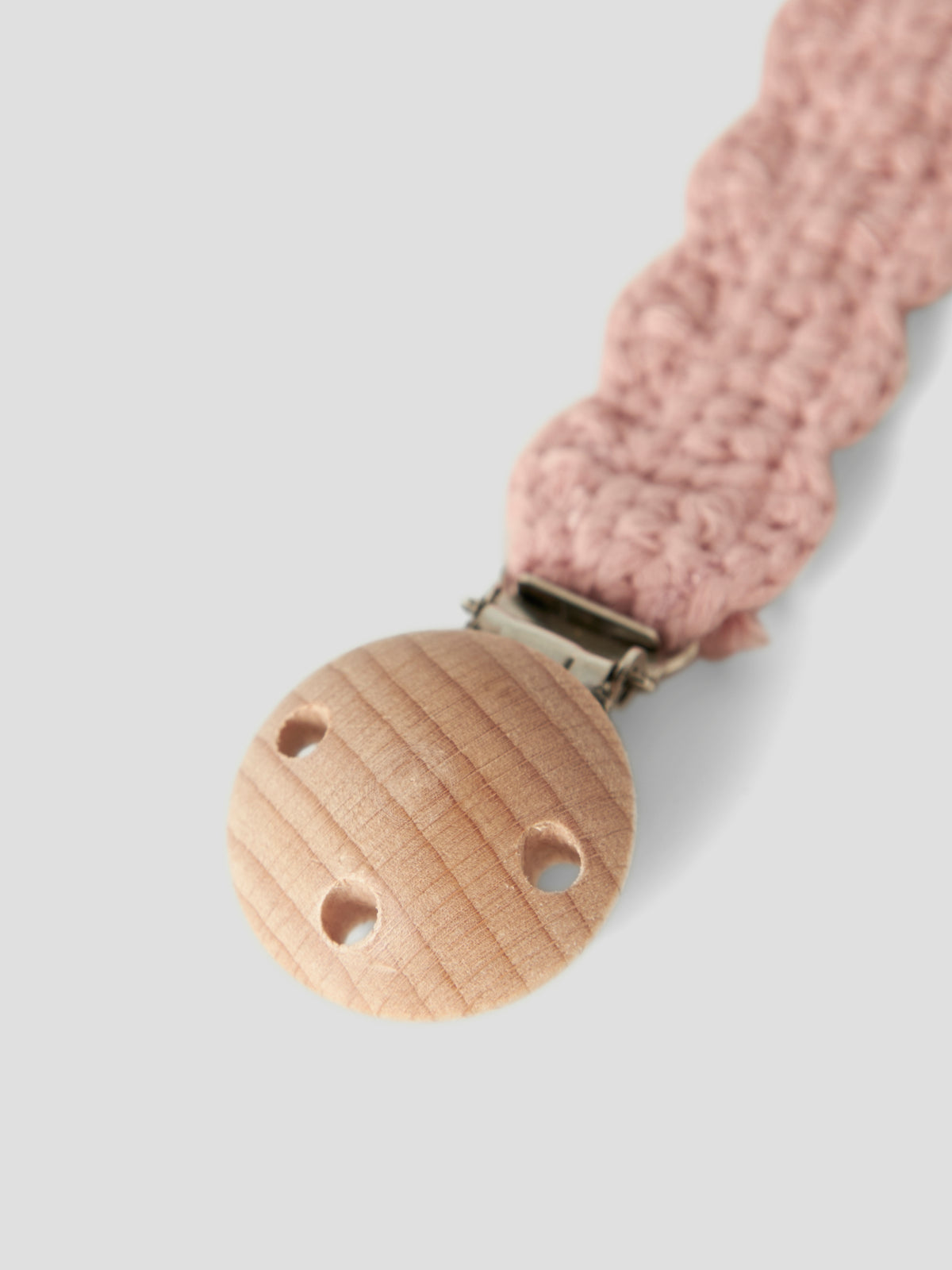 Detailaufnahme der Hvid Schnullerkette Nino aus rosafarbener Merinowolle mit naturfarbenem Holzclip. Erhältlich im Bärechind Winterthur.