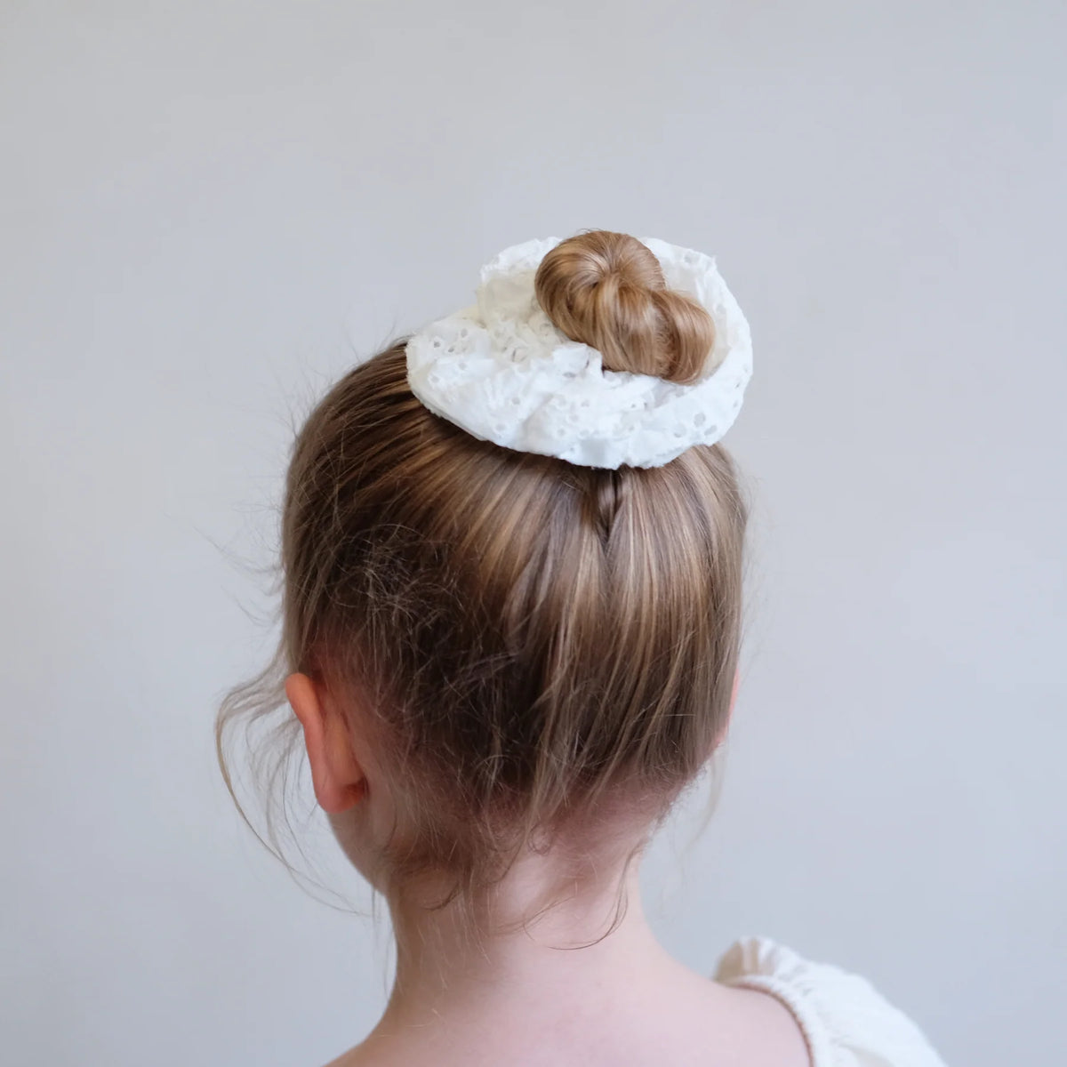 Kind mit Giant Broderie Anglaise Scrunchie – stilvolles Haargummi für moderne Hochsteckfrisuren, erhältlich in Winterthur, Zürich, Schweiz.