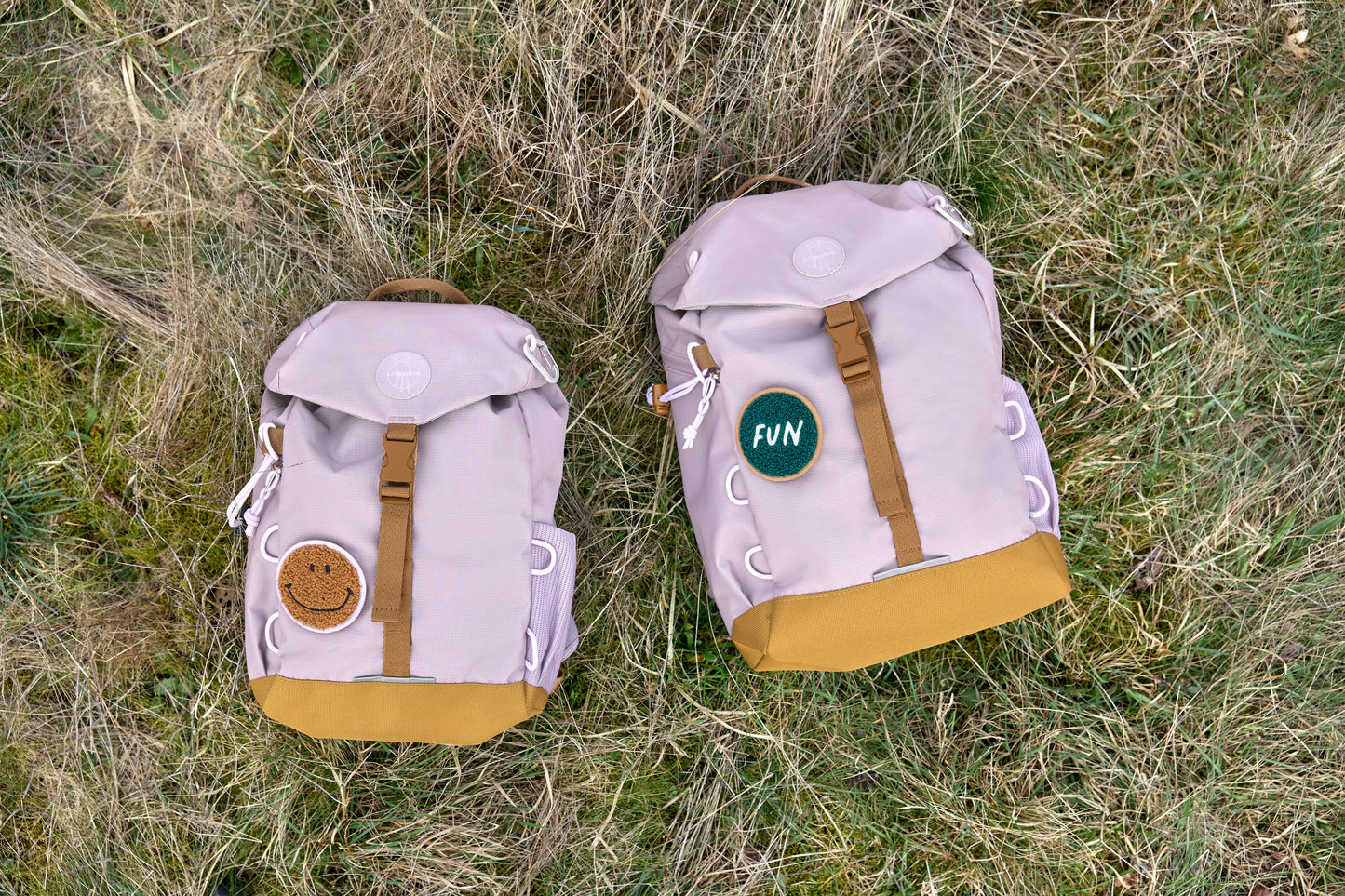 Zwei Lässig Wanderrucksäcke Little Gang in Lilac im Gras, nachhaltige Wahl für kleine Entdecker, im Bärechind Winterthur.