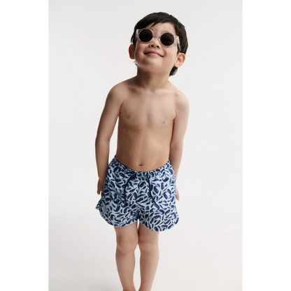 Kind trägt die Liewood Aiden Board Shorts in Ocean Pure Sky am Strand. UV-Schutz UPF 40+, schnell trocknend und bequem. Erhältlich in Winterthur, Zürich, Schweiz.