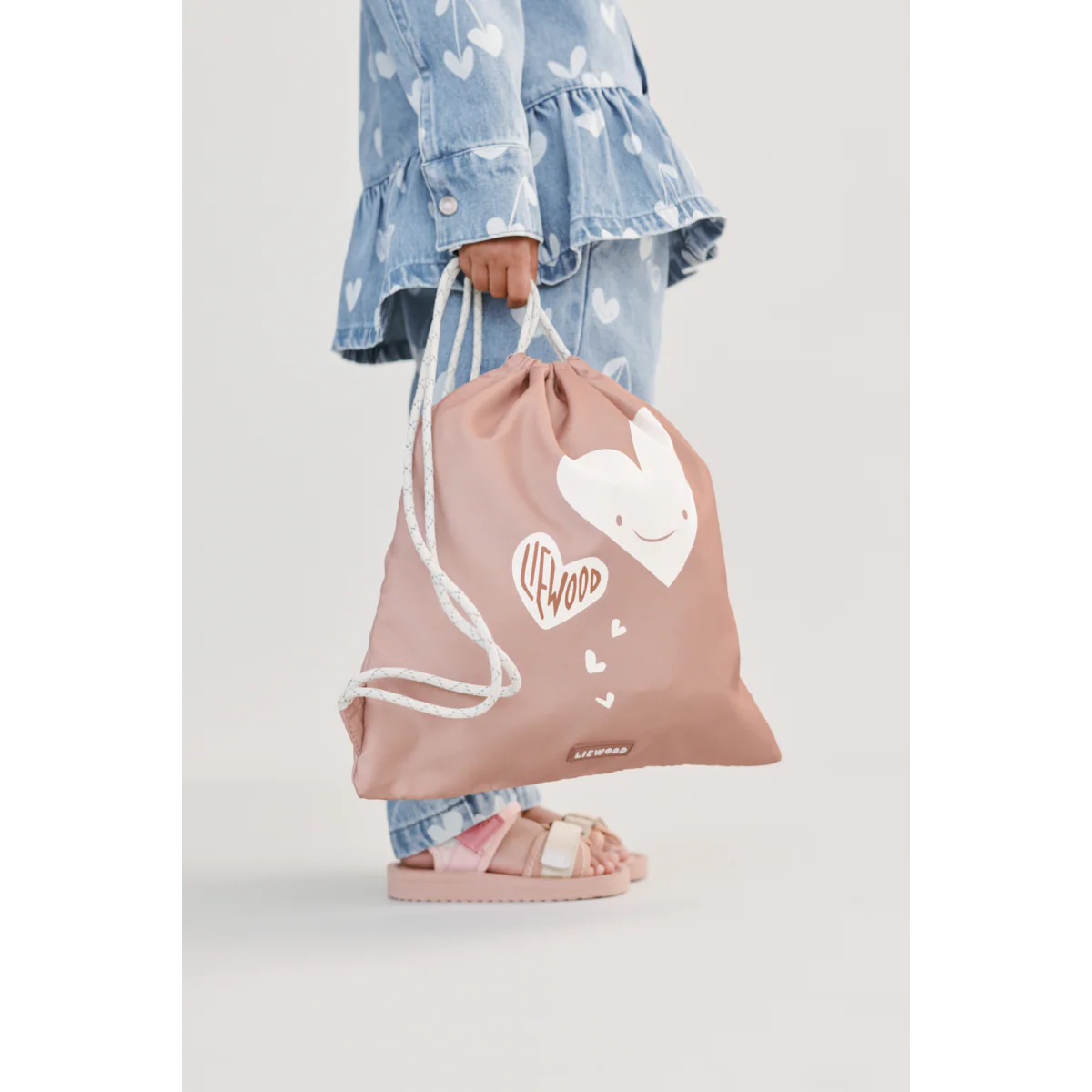 Kind trägt Liewood Danella Turnbeutel Hearts Pale Tuscany als Rucksack – nachhaltiges Kinderaccessoire bei Bärechind Winterthur, Zürich Schweiz.