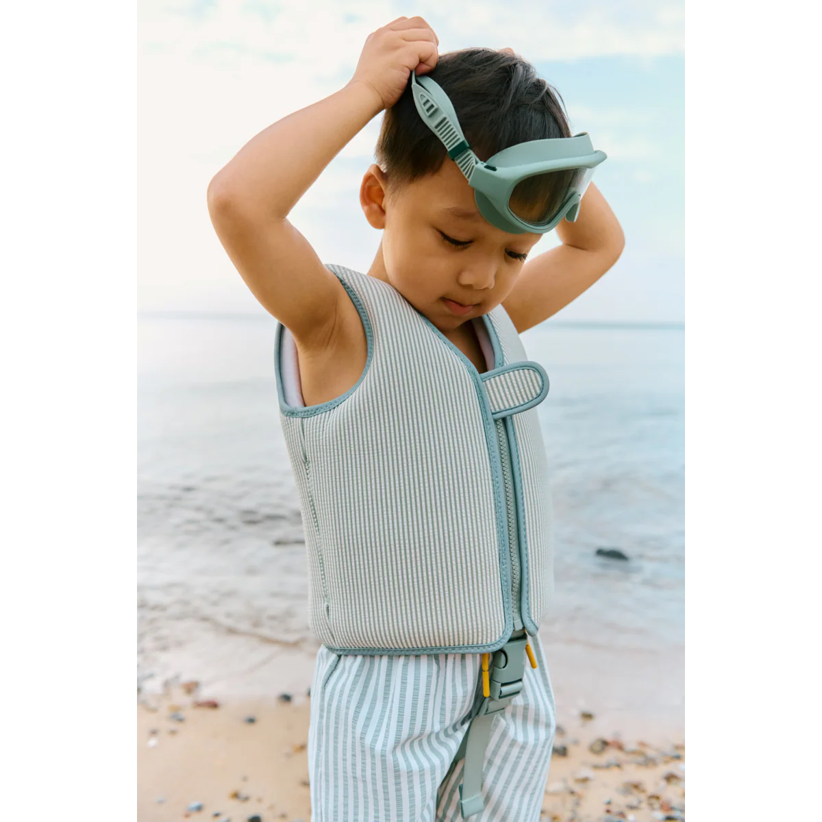 Kind trägt Liewood Dove Schwimmweste mit Streifen Peppermint Sandy am Strand – nachhaltige Kinder Bademode bei Bärechind Winterthur, Zürich Schweiz.