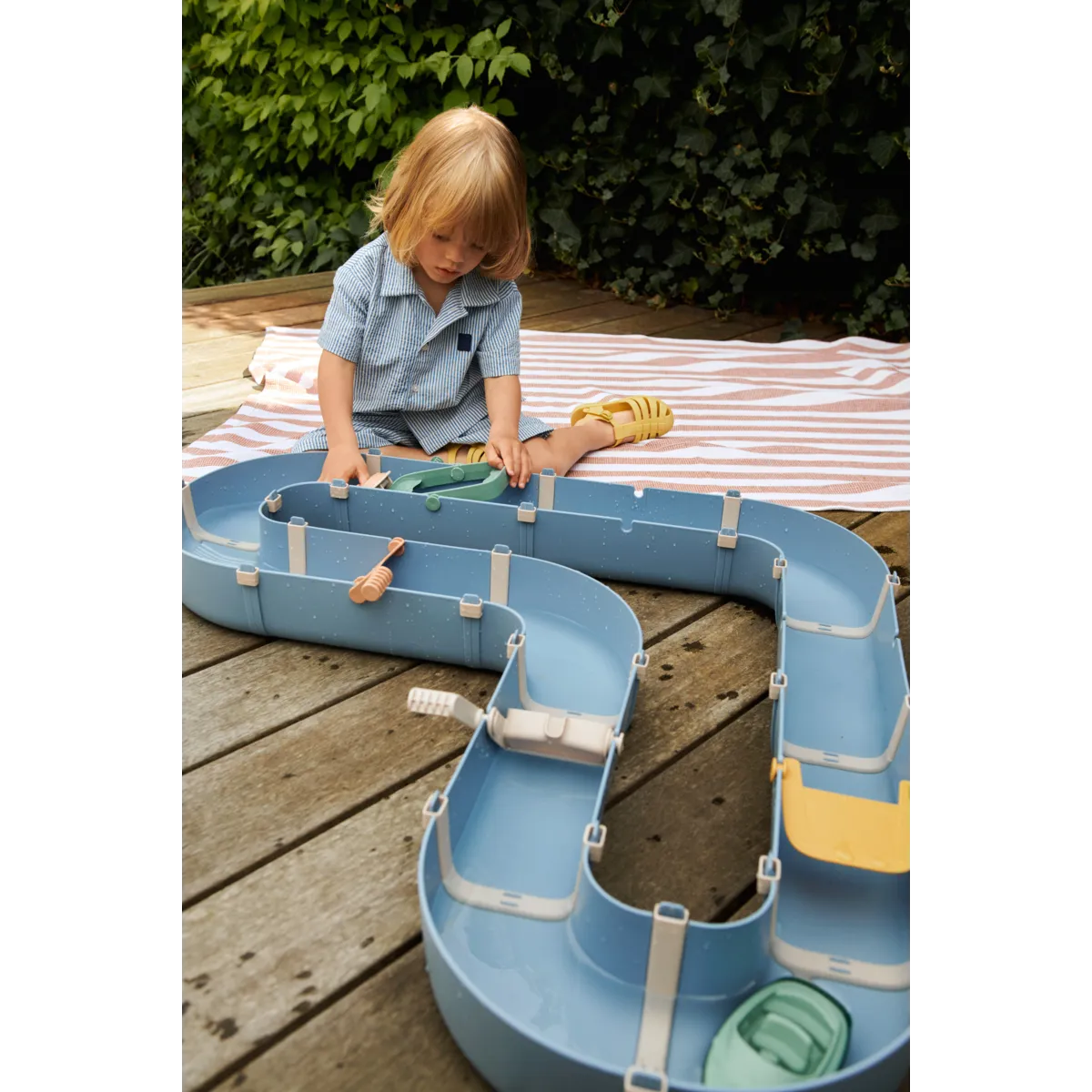 Kind spielt draussen mit der Liewood Wasserbahn, kreatives Wasserspielzeug im Bärechind Winterthur Zürich Schweiz.