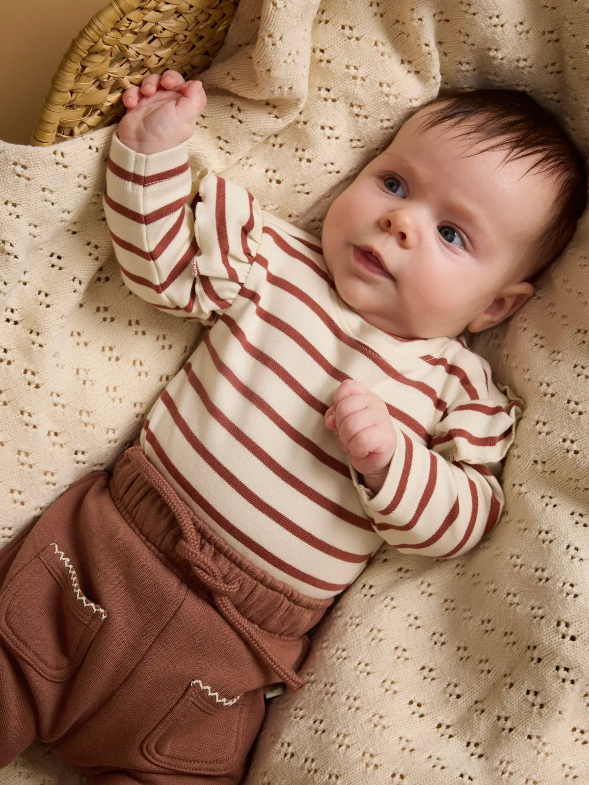 Baby trägt den gestreiften Lil' Atelier Body mit Rüschen, erhältlich im Bärechind.