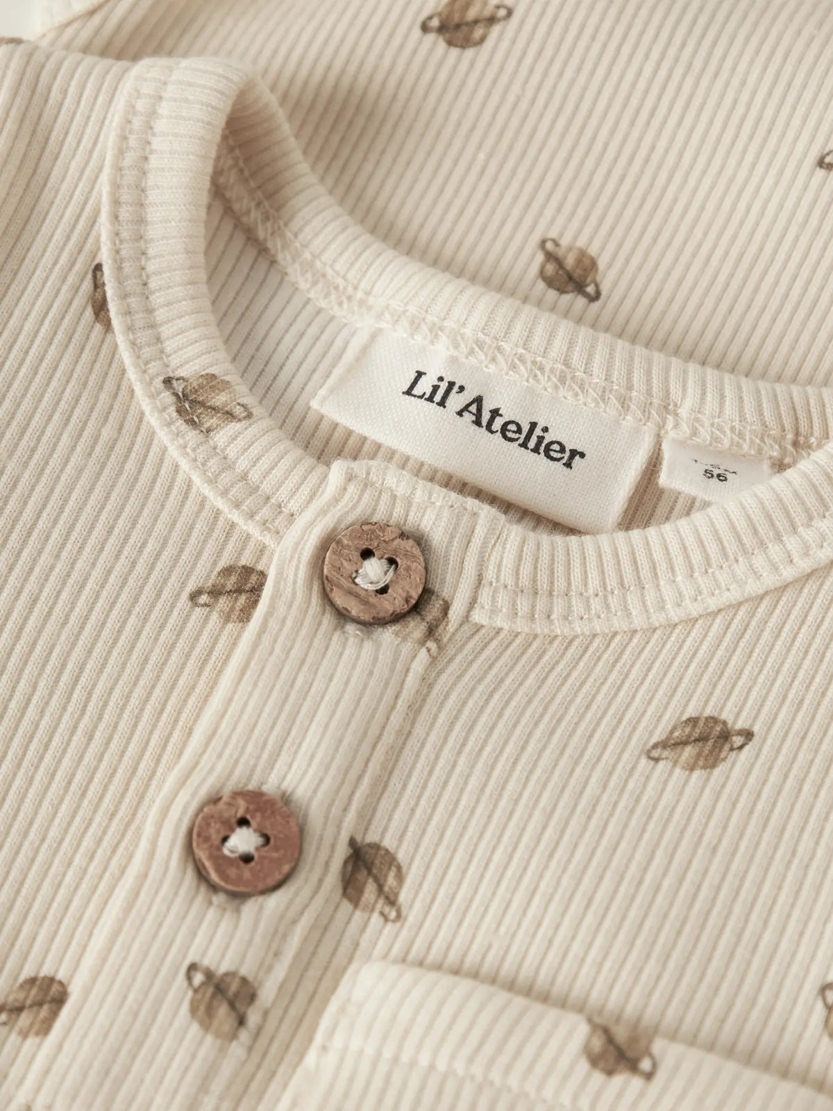 Detailaufnahme des LIL' ATELIER Ripp Bodys aus Baumwolle und TENCEL™ Lyocell mit Planetenprint, Knopfleiste und Brusttasche