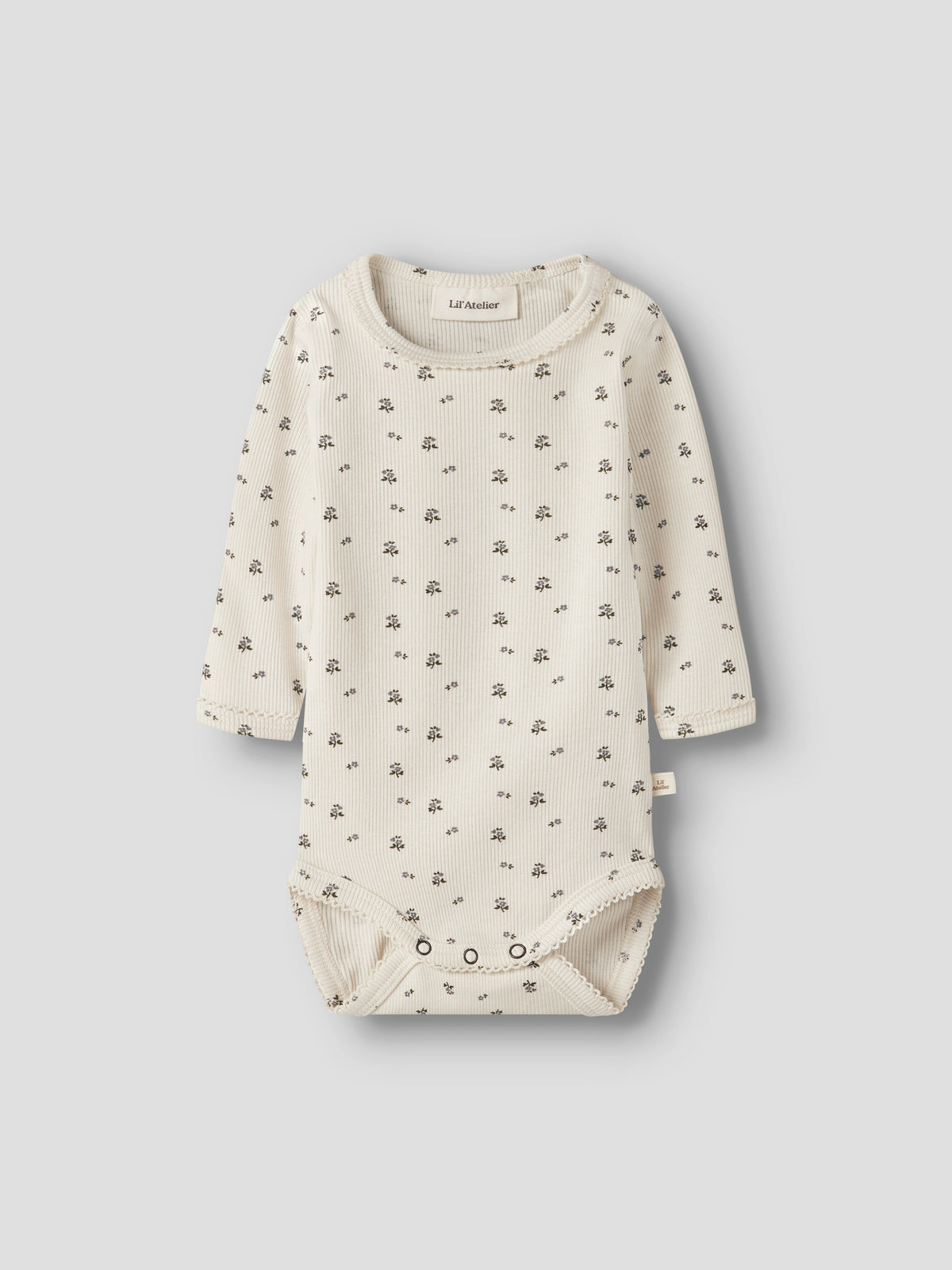 Lil' Atelier Rippbody in Creme mit feinem Blümchenmuster und langen Ärmeln.