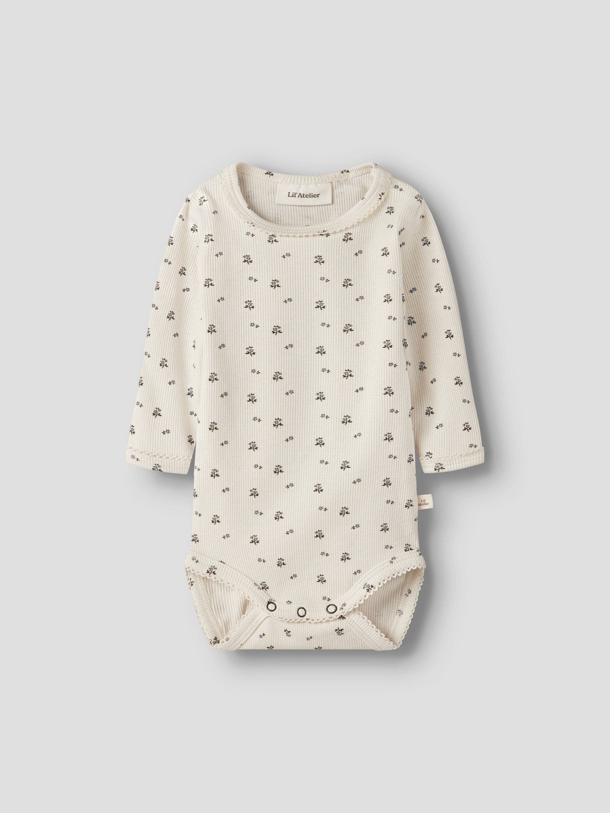 Lil' Atelier Rippbody in Creme mit feinem Blümchenmuster und langen Ärmeln.