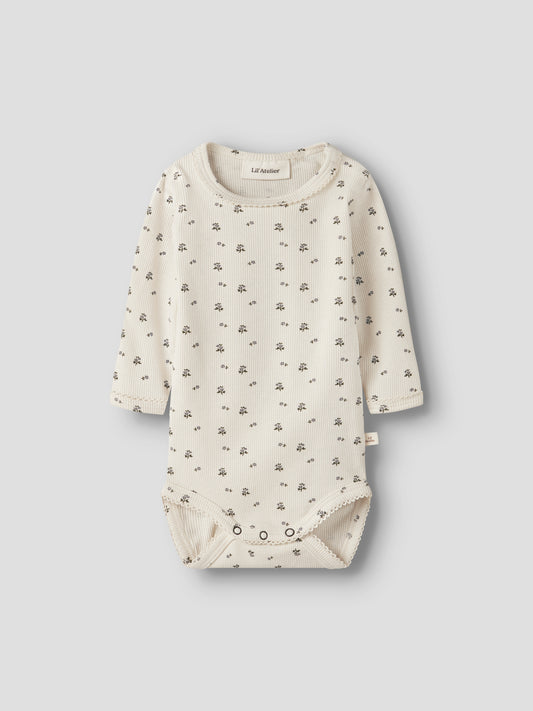 Lil' Atelier Rippbody in Creme mit feinem Blümchenmuster und langen Ärmeln.