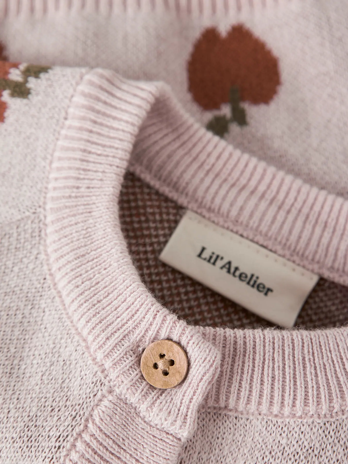 Detailaufnahme der Strickjacke mit Apfelmuster und Knopfleiste von LIL'ATELIER bei Bärechind Winterthur Zürich Schweiz