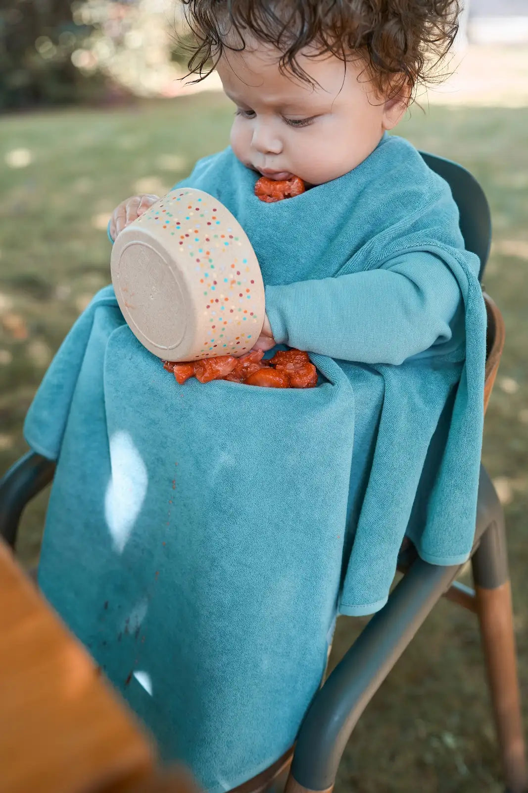 Kind trägt das wasserdichte Little Casimir Lätzchen Boo Dusty Ocean mit Ärmeln beim Essen und Spielen, erhältlich im Bärechind Winterthur