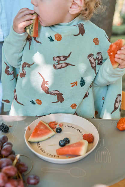 Baby trägt das wasserdichte Little Casimir Boo Lätzchen mit Otter-Motiv beim Essen – Bärechind Winterthur, Schweiz