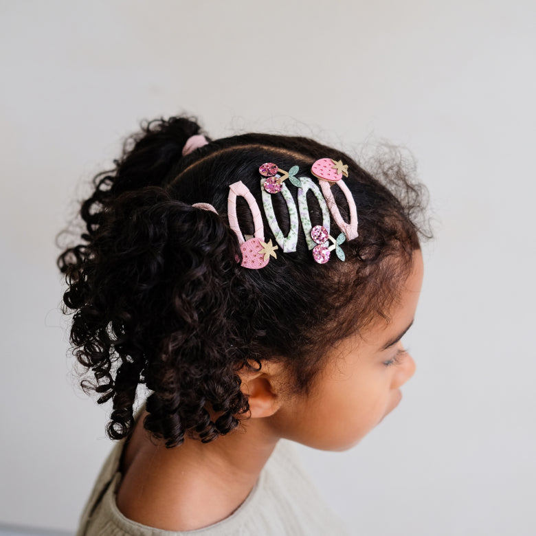 Kind mit fruchtigen Haarspangen von Mimi & Lula aus dem Kirschen und Erdbeeren Set im Bärechind Winterthur.