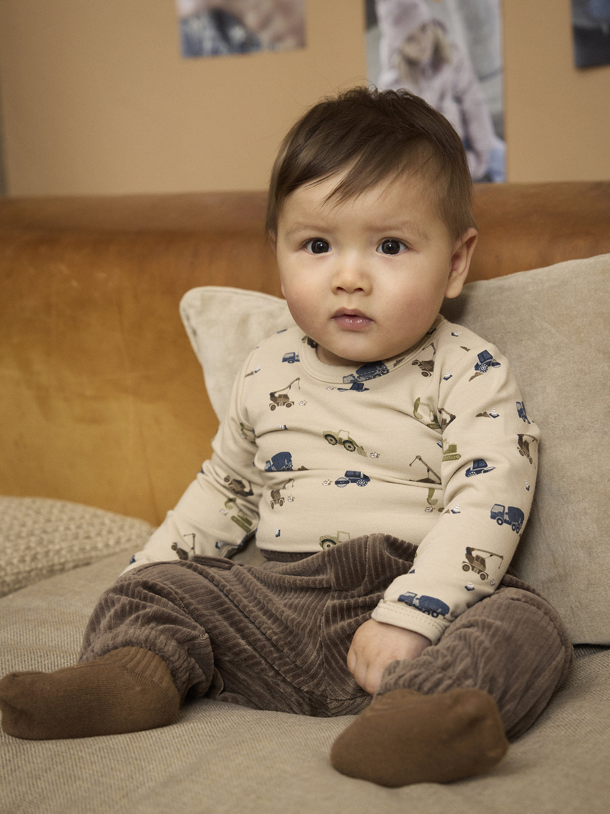 Baby trägt den Minymo Langarmbody mit Fahrzeugprint und brauner Hose, erhältlich im Bärechind Winterthur