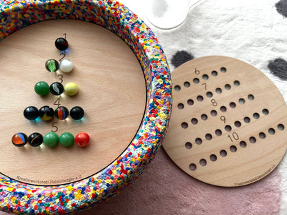 Das Montessori Rechenspiel aus Holz mit farbigen Murmeln fördert spielerisch das Zahlenverständnis und die Feinmotorik von Kindern. Erhältlich im Bärechind Winterthur.