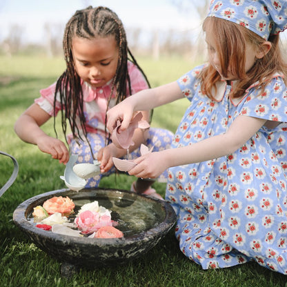 Kinder spielen draussen mit dem Mushie Whale Badespielzeug und entdecken das Schöpfen und Ausgiessen von Wasser.