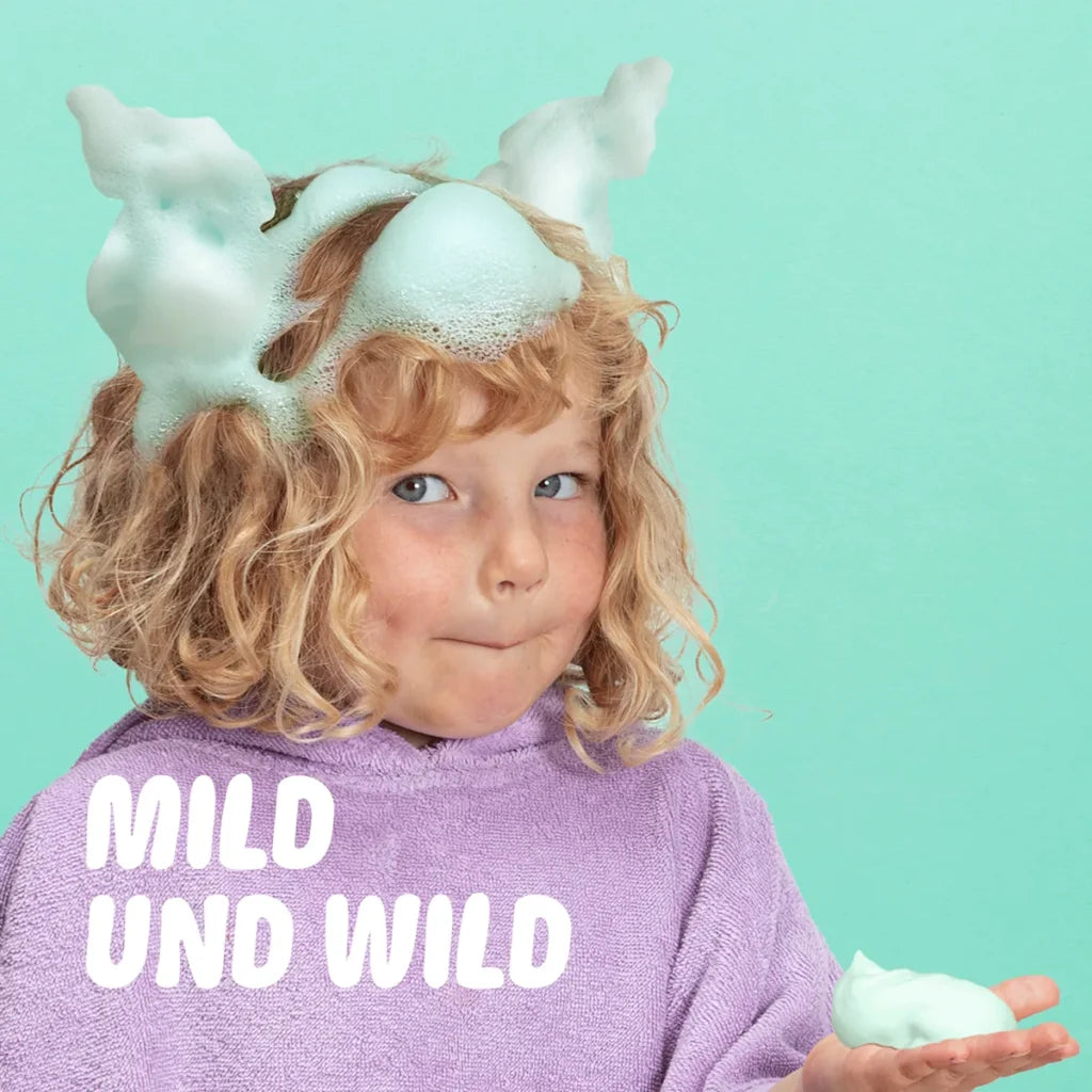 Kind spielt mit grünem Duschschaum von NAÏF in der Dusche, sanfte Kinderpflege erhältlich bei Bärechind Winterthur, Zürich, Schweiz.