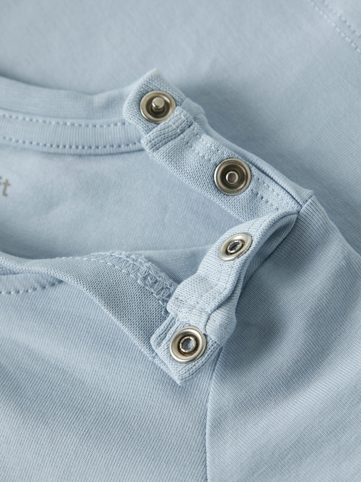 Detailaufnahme der Schulterdruckknöpfe am hellblauen Name It Kinder T-Shirt mit Löwenmotiv im Bärechind Winterthur