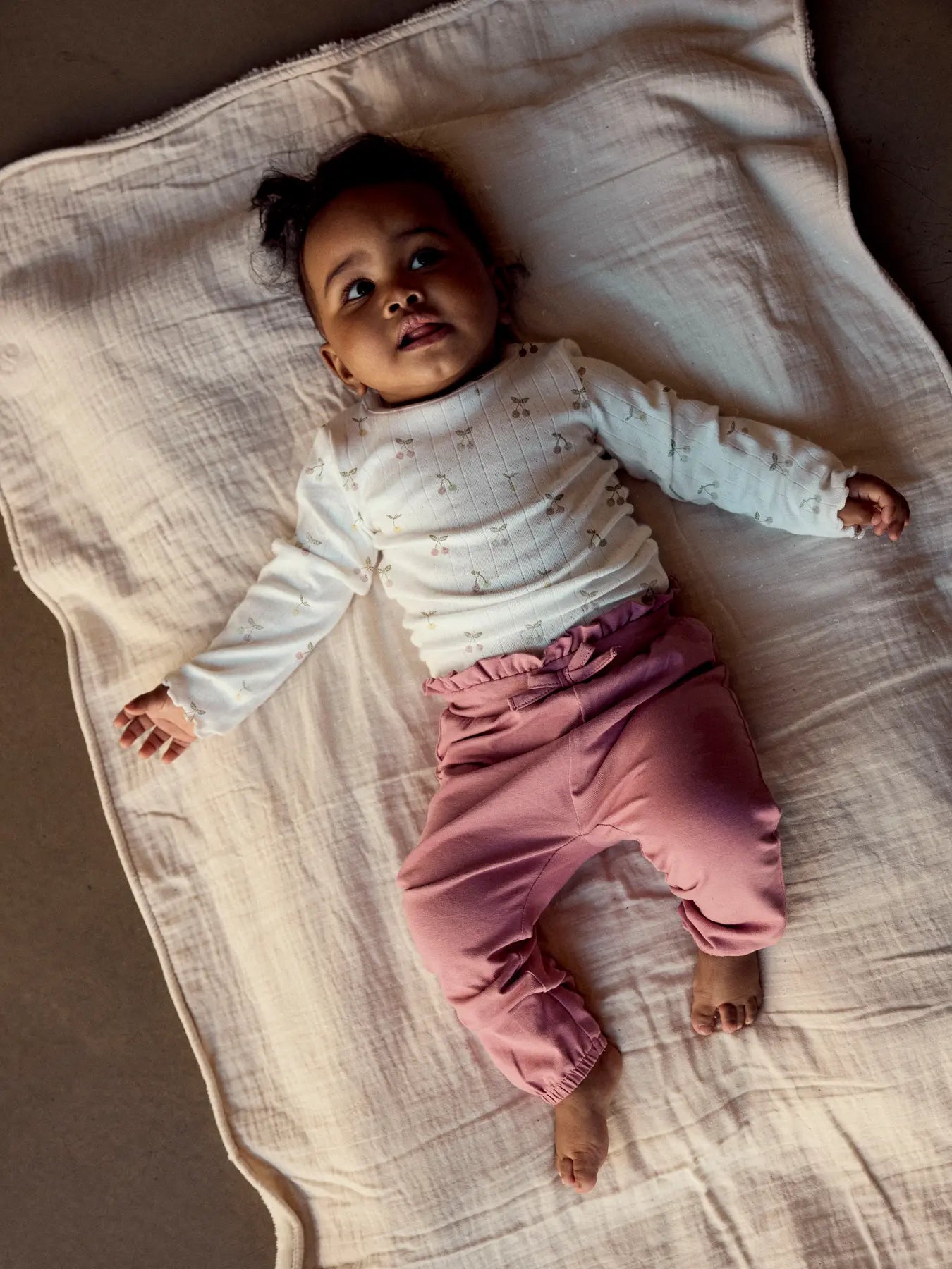Baby trägt NAME IT Langarm Body mit Kirsch Print in Creme zu kaufen im Bärechind Winterthur Zürich Schweiz.