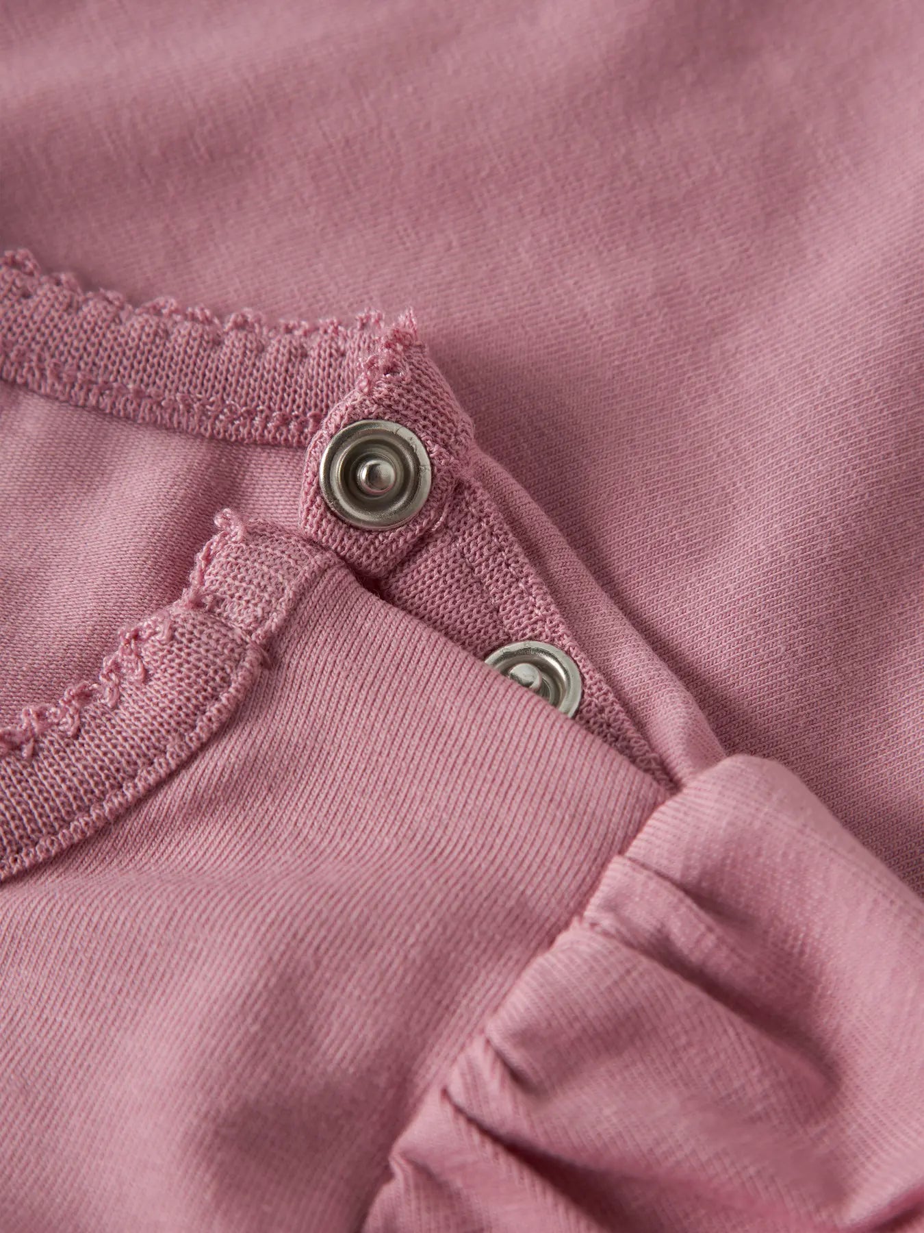 Detailaufnahme der Schulter mit Druckknöpfen und gerafftem Ärmel des NAME IT Langarmshirts.