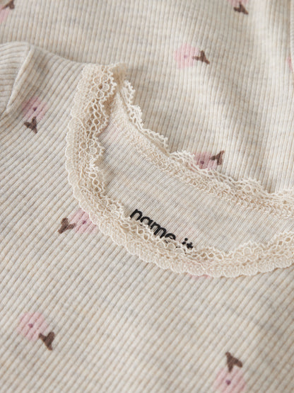 Detailaufnahme des NAME IT Ripp Bodys aus Baumwolle und TENCEL™ Lyocell in Creme mit rosa Blumenprint und feiner Spitzenkante, erhältlich im Bärechind Winterthur.