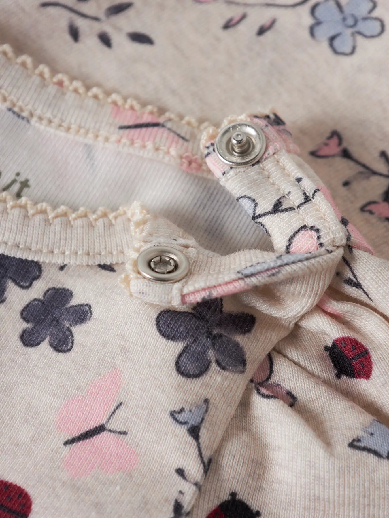 Detailaufnahme von Blumenmuster und Druckknöpfen auf einem NAME IT Babybody bei Bärechind Winterthur Zürich Schweiz