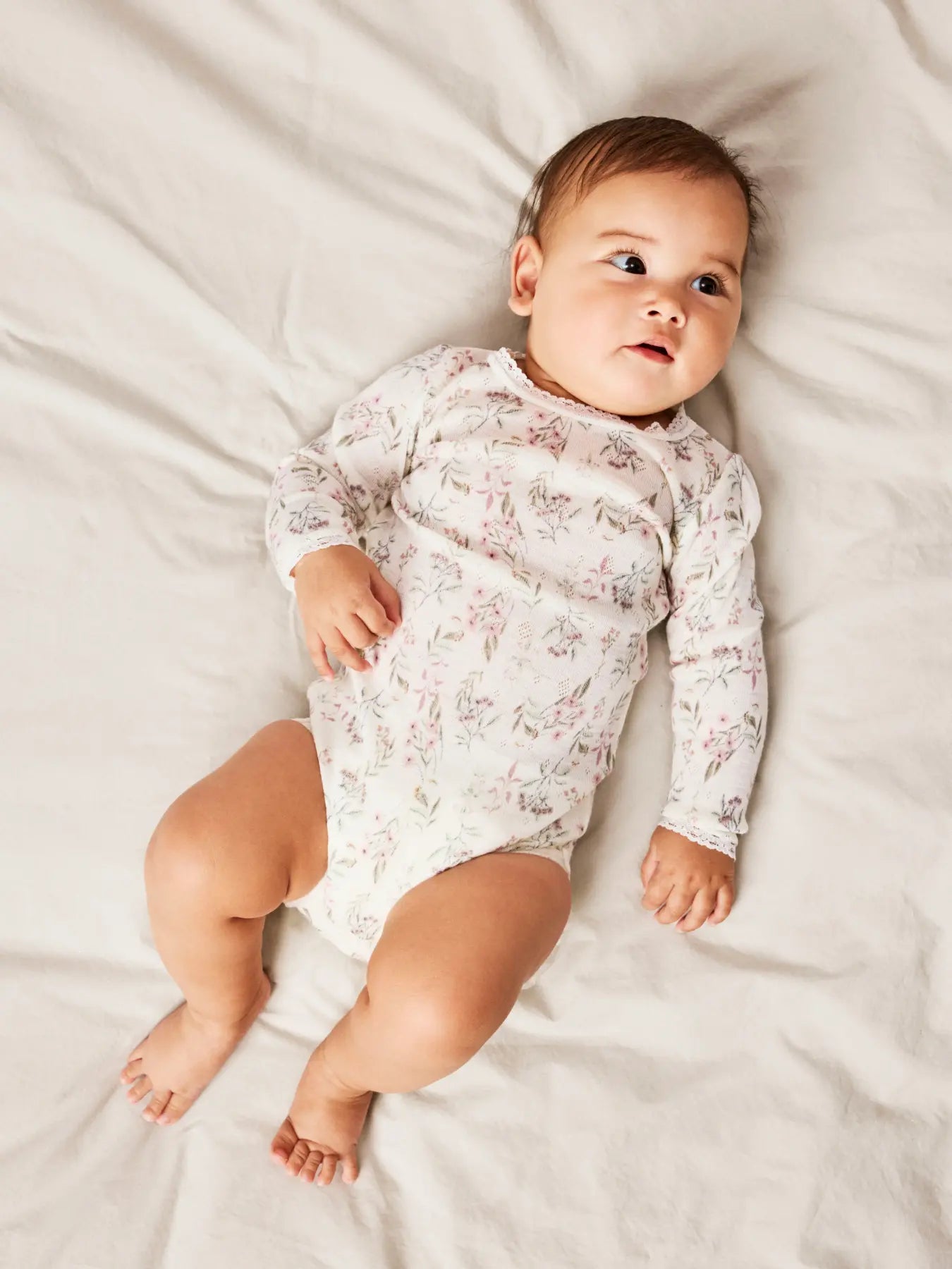 Baby trägt den Name it Merino Body mit Blumenmuster bei Bärechind