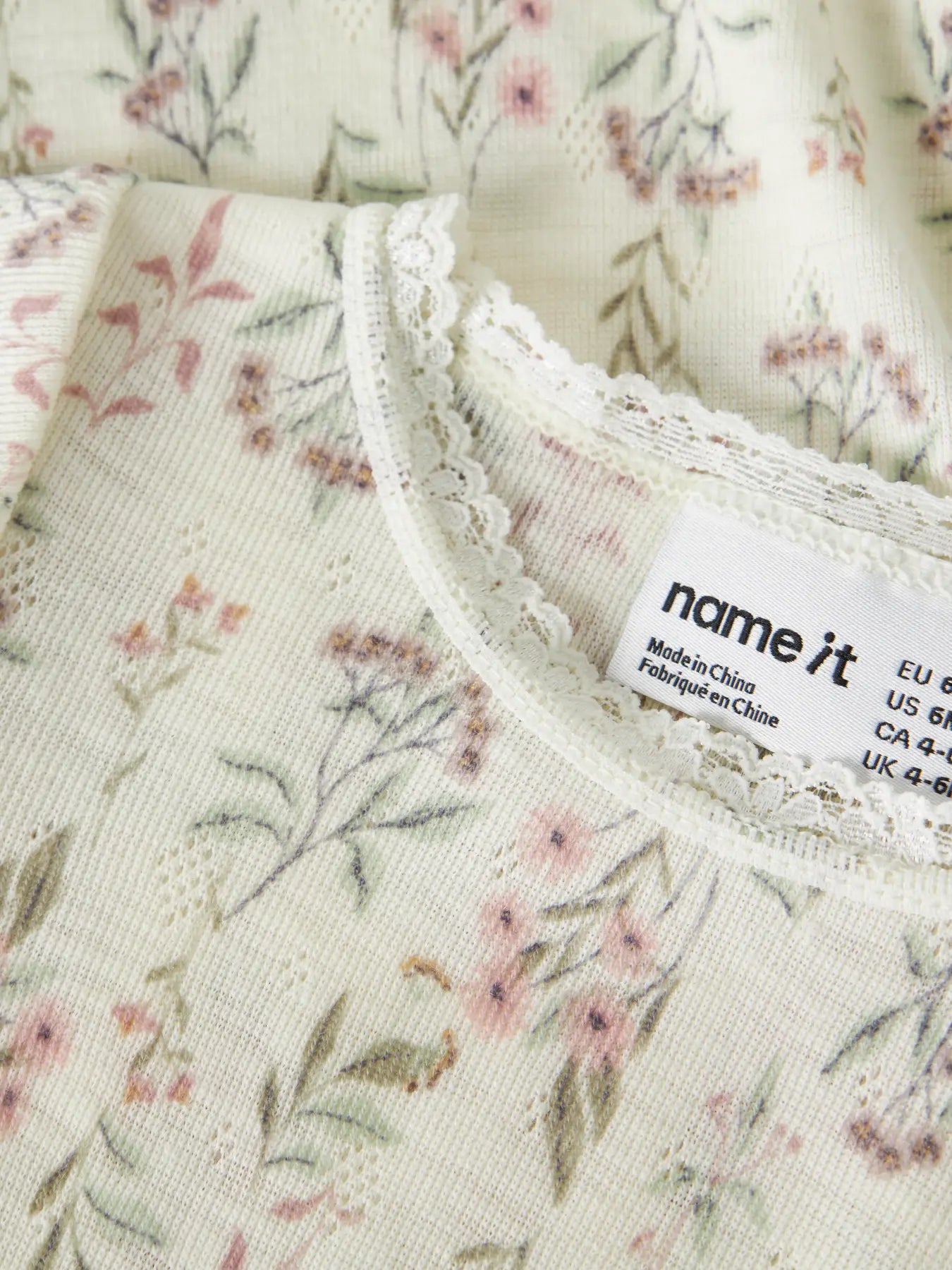 Detailaufnahme des Blumenmusters und Spitzenabschlusses am Merino Body