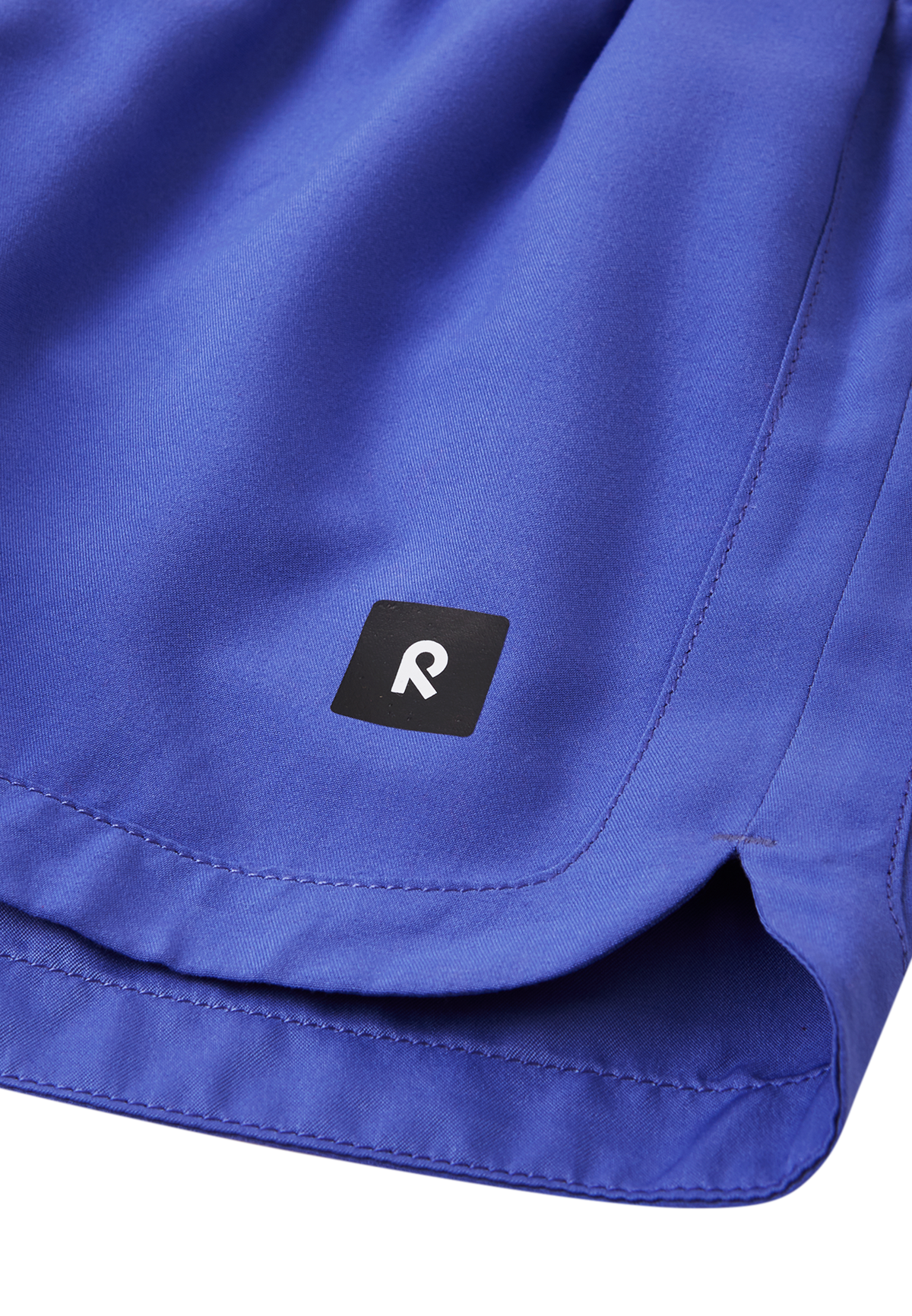 Detailaufnahme Logo & Saum der Reima Nauru Badeshorts – in Lila mit UV-Schutz
