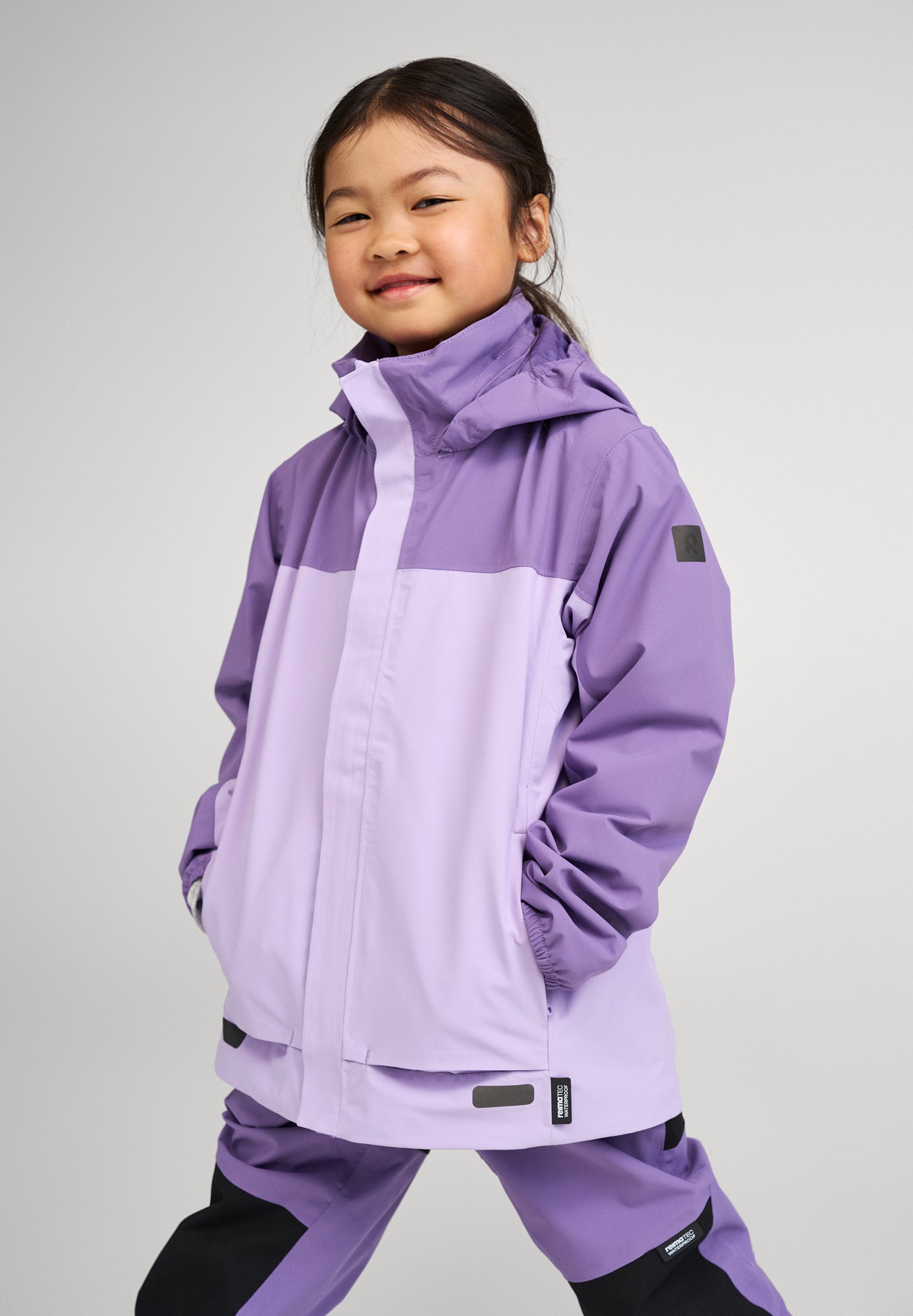 Kind trägt ReimaTec Regenjacke Salmi in Blooming Lilac bei Regenwetter