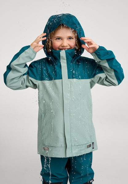 Kind trägt ReimaTec Regenjacke Salmi in Stone Green bei Regenwetter