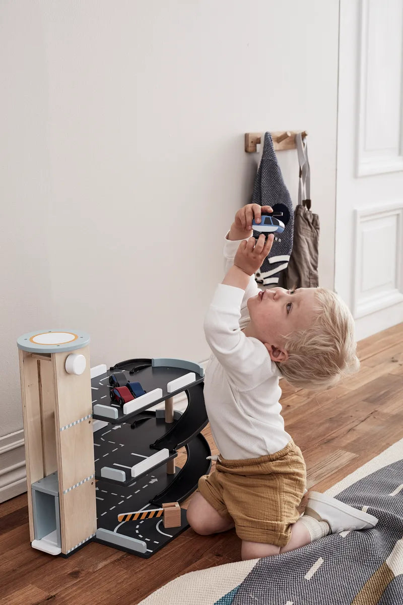 Kind spielt mit der Spielzeug Parkgarage AIDEN aus Holz von Kids Concept, zu kaufen bei Bärechind in Winterthur, Zürich, Schweiz.